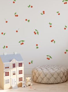 a doll house next to a wall with cherries on it