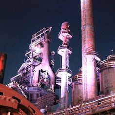 an industrial factory with large pipes and smokestacks on the top floor at night