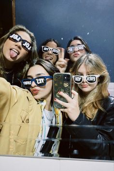 a group of people with fake glasses on their faces taking a selfie in front of a mirror