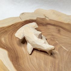 a small wooden dog figurine sitting on top of a piece of plywood