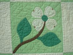 a green and white quilt with a flower on it