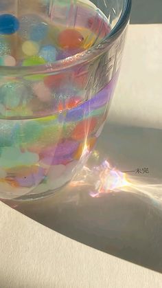 a glass filled with lots of different colored liquid sitting on top of a white table