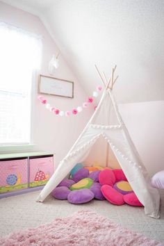 a child's bedroom with a teepee tent on the floor and pink rugs