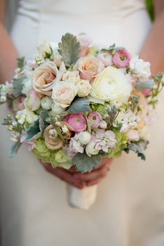 a bridal holding a bouquet of white and pink flowers with greenery on it