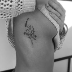 a black and white photo of a woman's back with flowers on her left side