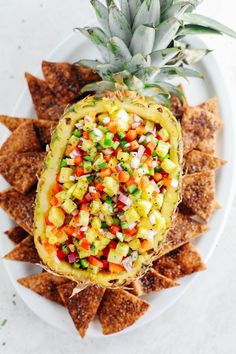 a pineapple is sitting on top of some tortilla chips with salsa in the middle