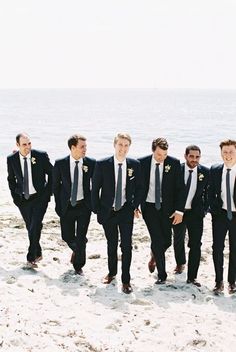 a group of men standing next to each other on top of a sandy beach