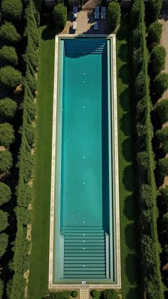 an aerial view of a swimming pool in the middle of a park with benches and trees