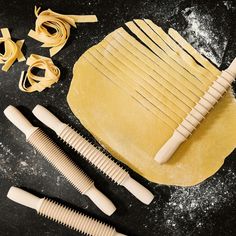 pasta being made with wooden utensils on a black counter top next to other items