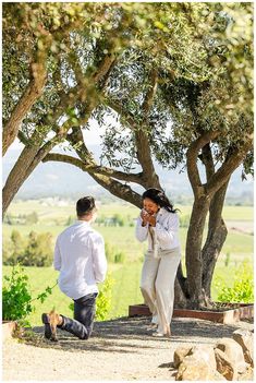 a man and woman are walking under some trees