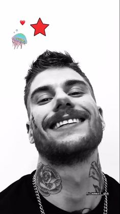 a man with tattoos and piercings smiles at the camera