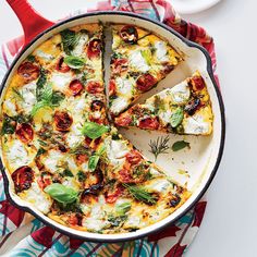 a pizza with cheese and tomatoes in a pan on a table next to a fork