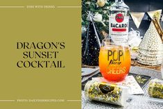 the dragon's sunset cocktail is sitting on a table next to bottles and glasses