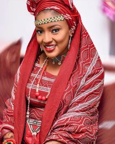 an african woman wearing a red scarf and headdress, smiling at the camera