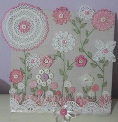 a card with pink and white flowers on the front, surrounded by crocheted doily