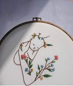 a close up of a embroidery on a hoop with flowers and a woman's face