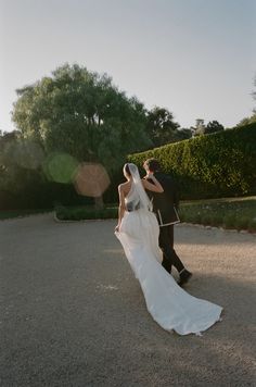 a bride and groom walking in the sun