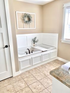 a bathroom with tile flooring and white cabinets in the corner next to a window