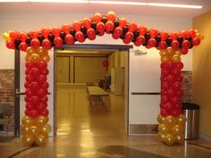 an arch made out of balloons in the middle of a room with tables and chairs