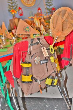 a back pack sitting on top of a red chair in front of a table filled with other items