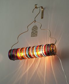 a multicolored light hanging from a metal hanger on a white wall next to a pair of scissors