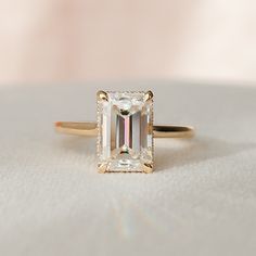 an emerald cut diamond ring on a white surface