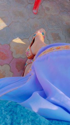 a woman's feet in sandals and a blue cloth on the ground next to a red frisbee