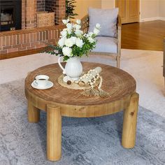 a coffee table with flowers in a vase on it and a chair next to it