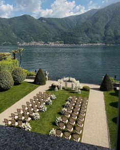 an outdoor ceremony set up with chairs and flowers on the lawn by the water's edge