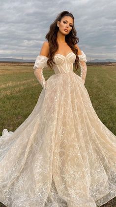 a woman in a wedding dress is standing in the grass with her hands on her hips