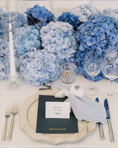 a place setting with blue hydrangeas and silverware