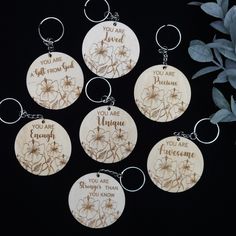 six wooden key chains with engraved words on them and flowers in the middle one is saying you are loved, you are awesome, you are enough