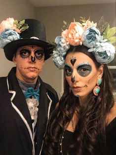 two people dressed up in costumes and makeup posing for the camera with flowers on their heads