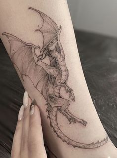 a woman's foot with a dragon tattoo on the left side of her leg