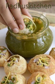 a person dipping something into a small bowl filled with green sauce on top of some food