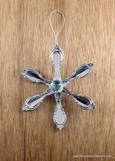 a silver cross ornament hanging on a wooden table