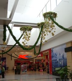 an indoor mall decorated with greenery and hanging ornaments