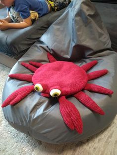 a little boy laying on top of a bean bag chair covered in a red crab