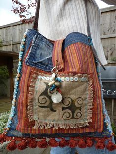 a woman is holding a purse made out of old jeans and other fabric materials