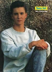 a young man leaning against a wall with his hands on his knees and looking at the camera