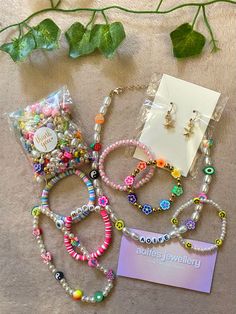 several bracelets and earring sets are laid out on the floor next to a plant