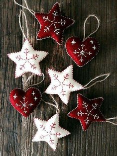 four red and white ornaments hanging from string on wooden surface with snowflakes