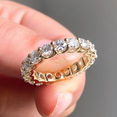 a close up of a person's hand holding a gold ring with diamonds on it