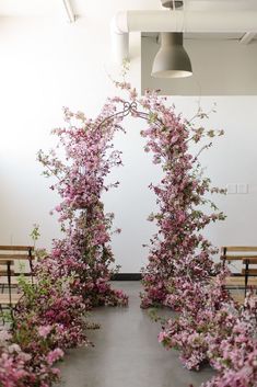 pink flowers are blooming in the middle of a room with benches and lights hanging from the ceiling