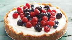 a cake topped with berries and cream on top of a white counter next to a cup