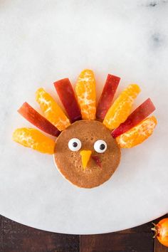 a turkey made out of fruit on top of a white plate with an orange slice