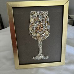 a wine glass made out of buttons in a gold frame