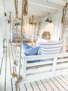 a white porch swing with blue pillows on it