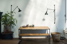 a wooden table sitting in front of a window next to a lamp and potted plant