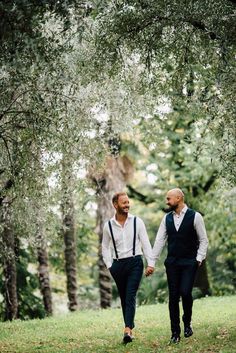 two men are walking through the woods holding hands